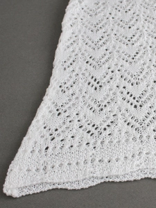 Close-up of white pointelle knit fabric showing intricate wave pattern and soft texture