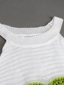 Close-up of white knit tank top with hollow-out texture and green trim on collar