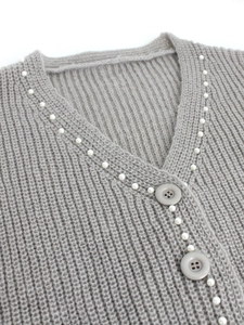 Vue détaillée du cardigan en maille grise avec bordure en perles et grands boutons