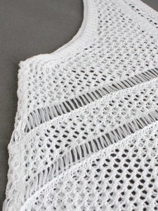 Gilet en tricot crochet blanc avec texture géométrique ajourée et franges pour les vacances