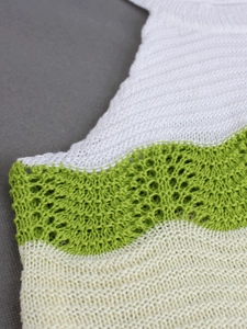 Macro view of wave patterned knit vest with hollow out crochet details in three colors