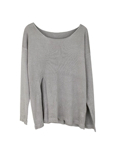 Detailed view of the side slit on a gray fine-knit long sleeve pullover sweater