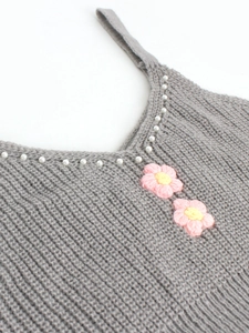 Détail du haut en maille côtelée grise avec perles et fleurs crochetées main