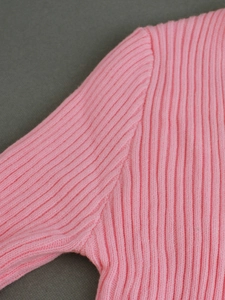 Dettaglio macro del cardigan rosa a coste con cuciture rifinite sulla spalla