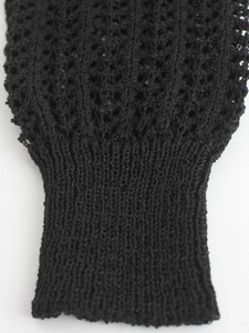 Detail of black knit cardigan showing intricate crochet pattern and ribbed cuff texture