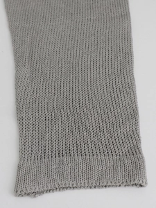Detailed macro view showing the fine knit texture and ribbed cuff of the grey sweater sleeve