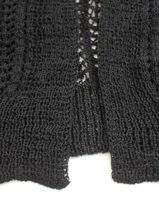 Detailed close-up of black hollow-out crochet knit pattern and ribbed hem on the cardigan