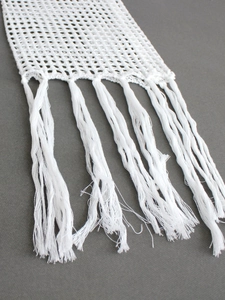 Détail d'un haut de plage en crochet blanc avec maille ajourée et longues franges