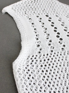 Detailed macro shot of white hollow knit wave pattern on an off-shoulder summer dress