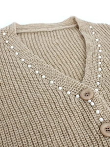 Détail du cardigan en maille kaki montrant le col en V avec perles et boutons marrons
