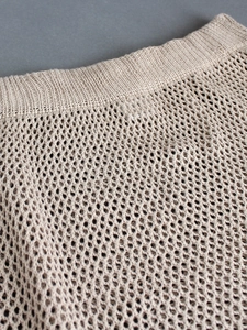 Detailed close-up of beige knit mesh dress featuring ribbed waistband and hollow-out texture