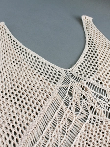 Détail du col en V avec des motifs ajourés au crochet sur cette robe beige crème