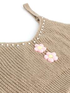 Détail d'un caraco en maille avec bordure en perles et fleurs au crochet 3D roses