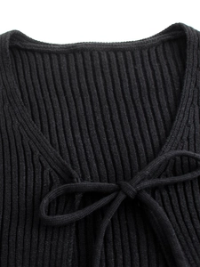 Dettaglio del cardigan nero in maglia a coste con scollo a V e fiocco decorativo frontale