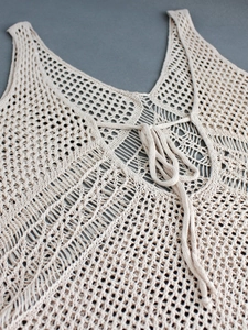 Détail macro de la robe crochet beige avec col en V, texture ajourée et cordons de serrage