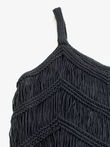 Détail de tricot bohème ajouré avec des franges à pompons noirs et une texture tissée