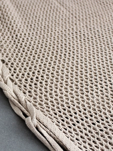 Detailed macro view of beige hollow-out knit dress with intricate mesh pattern