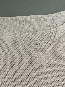 Close-up of fine knit beige sweater showing smooth neckline and soft needlework texture