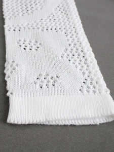 Detailed close-up of white knit dress sleeve with delicate geometric hollow-out patterns