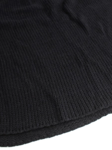 Detailed close-up of black ribbed knit sweater hem showing thick vertical texture