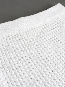 Detail of white knitted mesh texture and ribbed hem on a beach cover-up dress