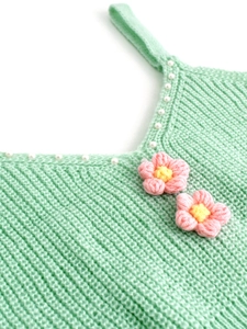 Détail du caraco en maille vert menthe avec perles blanches et fleurs au crochet