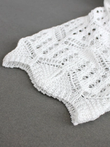 Détail macro de maille crochetée blanche aux motifs géométriques et bord ondulé