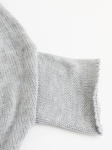 Close-up of casual grey knit sweater sleeve featuring high-quality rolled cuff detail