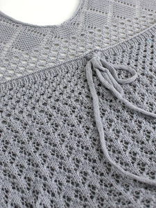 Detailed macro view of grey knit hollow-out fabric with diamond mesh and drawstring