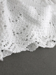 Textura detallada de cárdigan playero de punto blanco con diseño de malla calada