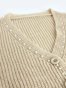 Vue détaillée du gilet en maille beige avec bordure en perles et boutons élégants