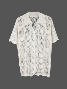 Détail de la texture tricotée ajourée et boutons blancs sur un cardigan crème court