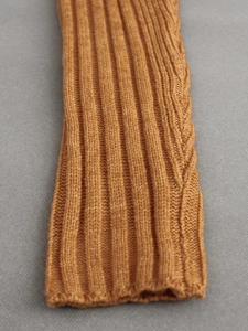 Detail shot of ginger yellow knit sleeve featuring vertical ribs and cable knit texture
