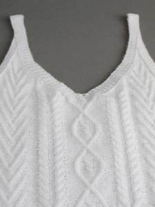 Détail du caraco en tricot blanc présentant des motifs de torsades et de losanges