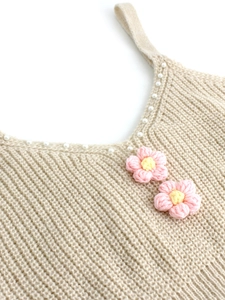 Texture de maille détaillée avec perles et fleurs au crochet roses sur le cardigan