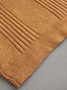 Detailed macro view of ginger yellow rib-knit cuff on a long sleeve turtleneck sweater
