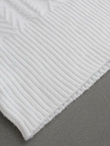 Gros plan sur la maille torsadée blanche et la texture côtelée du gilet d'été