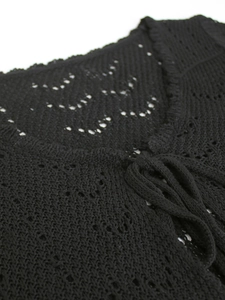Detalle de cárdigan playero negro de punto calado con textura de malla y cierre de cordones