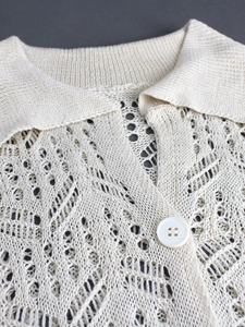 Détail d'un cardigan en maille ajourée blanc crème avec une texture complexe