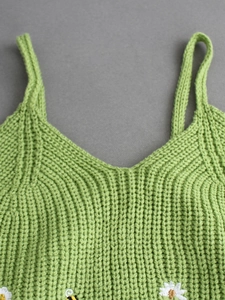 Detailed knit texture of light green camisole with delicate white daisy embroidery