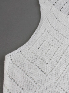 Vue détaillée du motif en tricot évidé blanc et des détails géométriques de la maille