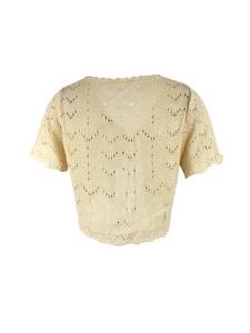 Detalle del top beige de punto calado con textura de ganchillo y dobladillo ondulado