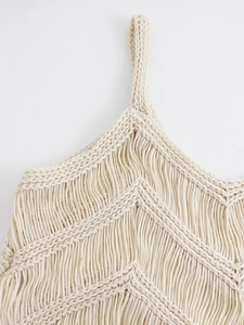 Détail d'un haut en crochet blanc cassé avec motif en V et franges de style bohème
