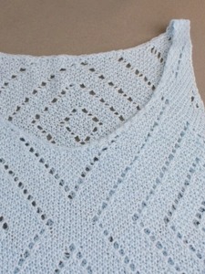 Gros plan sur le gilet en maille bleu clair avec motifs ajourés et vagues