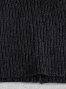 Detailed macro shot of black ribbed knit fabric texture on a two-piece sweater set