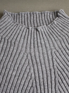 Detail of grey ribbed knit long sleeve sweater featuring a classic round neckline