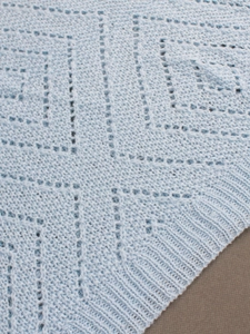 Vue détaillée du tricot pointelle bleu clair avec motif géométrique ajouré élégant