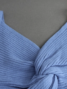 Detail view of the blue ribbed knit V-neck tank top featuring a front twist knot design