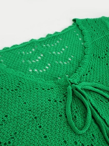 Detalle de top de punto crochet verde brillante con cuello en V y encaje delicado