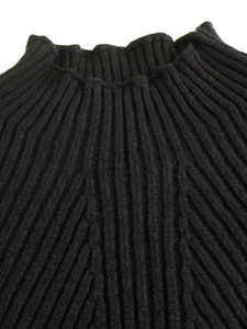 Macro detail of black long-sleeved sweater showing premium thick ribbed knit texture
